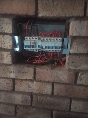 Circuit breakers recessed into a brick wall during an outdoor DB rewiring job